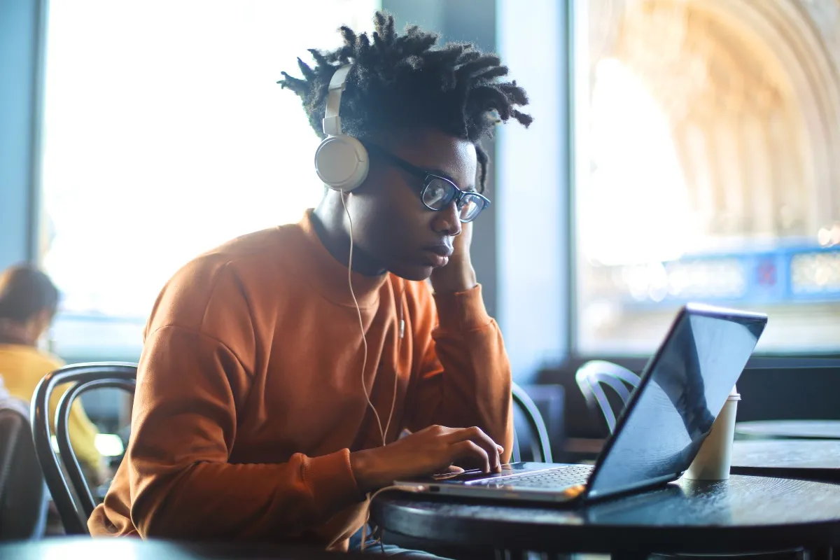Young adult focused on learning at a laptop, wearing headphones